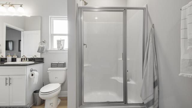 full bathroom featuring a stall shower, baseboards, toilet, wood finished floors, and vanity