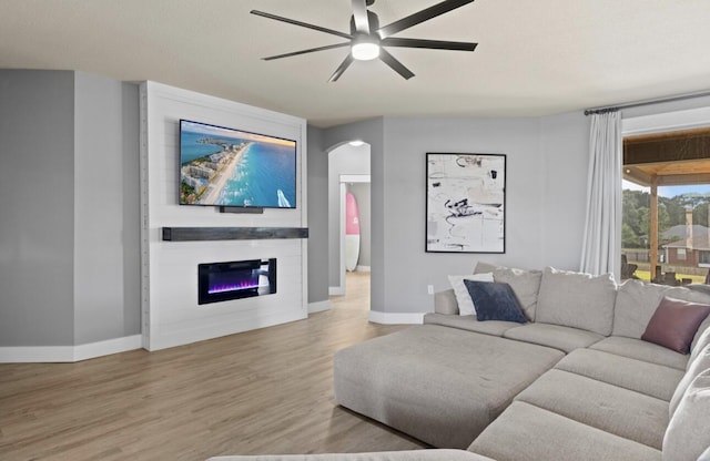 living room featuring ceiling fan, a fireplace, and light hardwood / wood-style floors