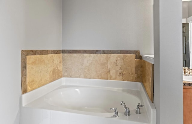 bathroom featuring a relaxing tiled tub and vanity