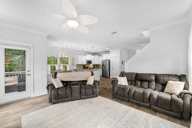 living room with ornamental molding, ceiling fan, and light hardwood / wood-style floors