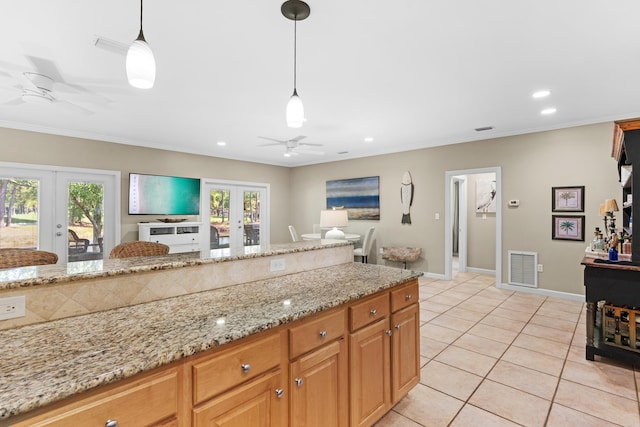 kitchen with french doors, light tile patterned floors, light stone counters, and hanging light fixtures