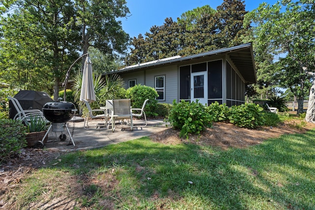 back of house with a sunroom, a patio area, and a yard