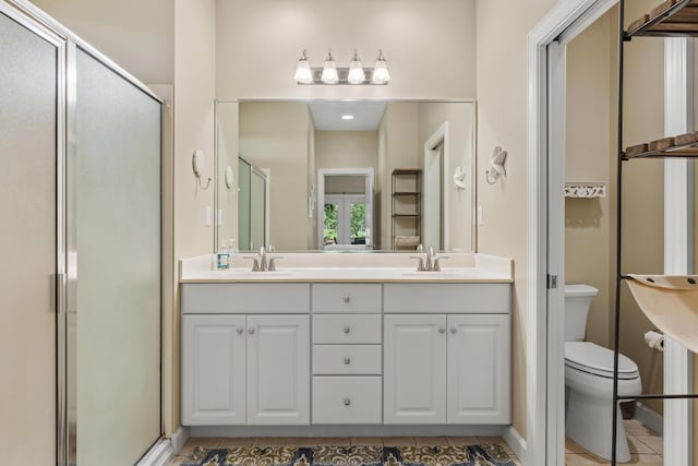 bathroom featuring tile patterned flooring, vanity, a shower with door, and toilet