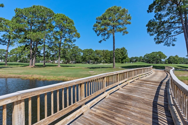 view of dock with a lawn and a water view