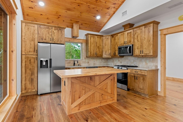 kitchen featuring light hardwood / wood-style flooring, vaulted ceiling, appliances with stainless steel finishes, wooden counters, and a kitchen island