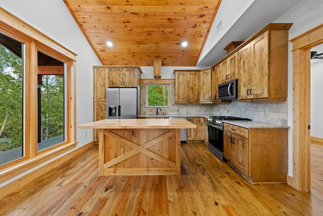 kitchen featuring vaulted ceiling, appliances with stainless steel finishes, a center island, butcher block counters, and light wood-type flooring