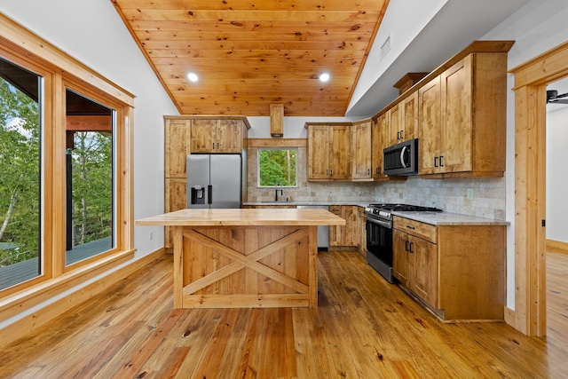 kitchen with lofted ceiling, stainless steel appliances, light hardwood / wood-style floors, and backsplash