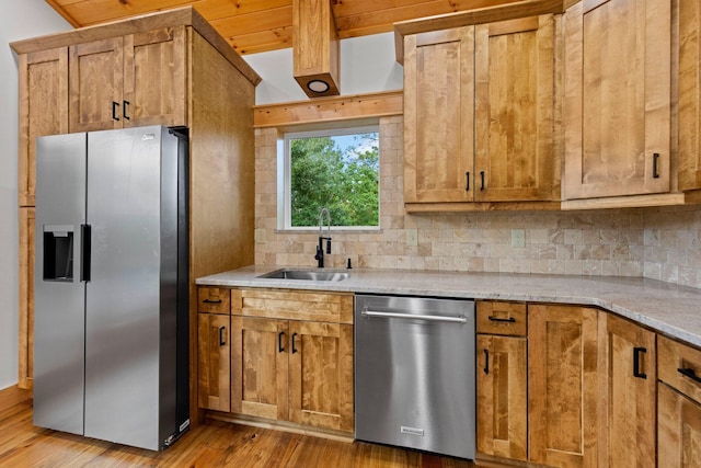 kitchen with sink, light hardwood / wood-style flooring, appliances with stainless steel finishes, tasteful backsplash, and light stone countertops