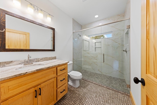 bathroom featuring vanity, a shower with door, and toilet