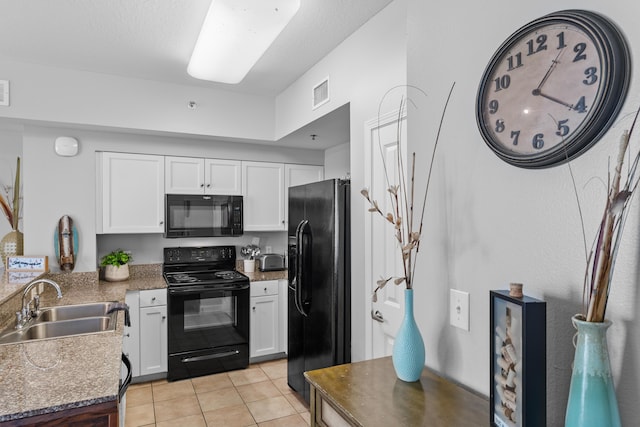 kitchen with sink, light tile patterned floors, white cabinets, and black appliances