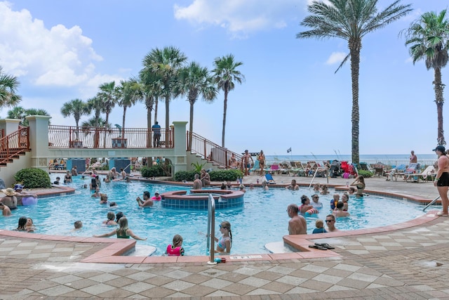 view of swimming pool with a patio, a hot tub, and a water view