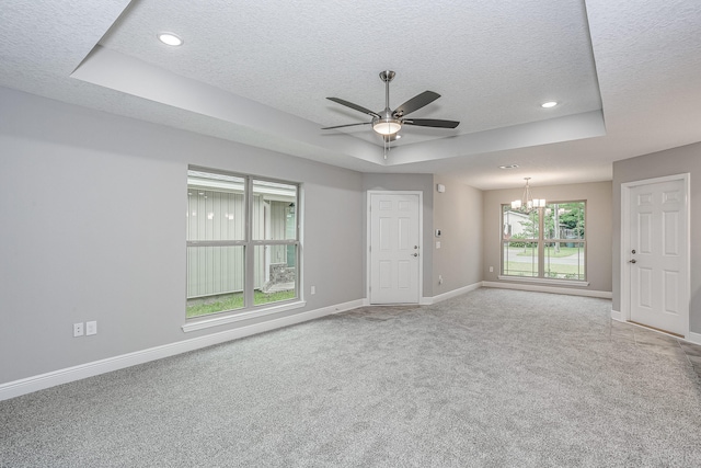 carpeted empty room featuring a textured ceiling, a tray ceiling, and ceiling fan with notable chandelier