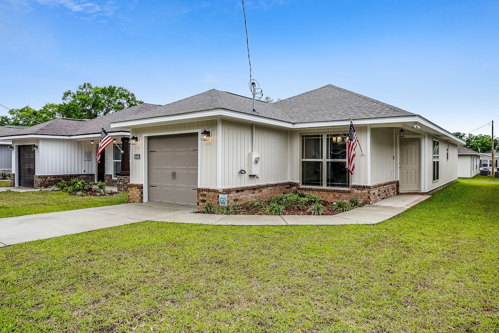 675 Passion Flower St, Defuniak Springs, FL 32433 - ranch-style home with brick siding, a garage, concrete driveway, a front yard, and roof with shingles