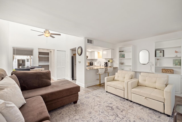 living room with ceiling fan, sink, and light hardwood / wood-style floors