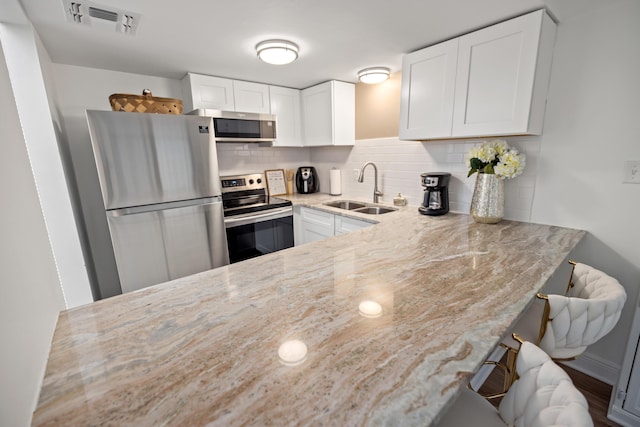 kitchen with white cabinetry, stainless steel appliances, sink, and decorative backsplash