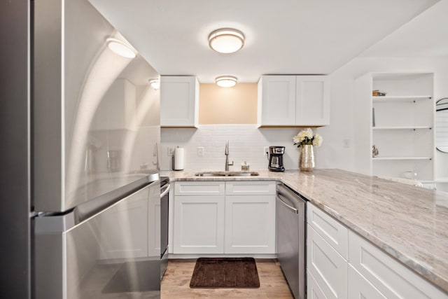 kitchen with light stone counters, sink, white cabinets, and appliances with stainless steel finishes