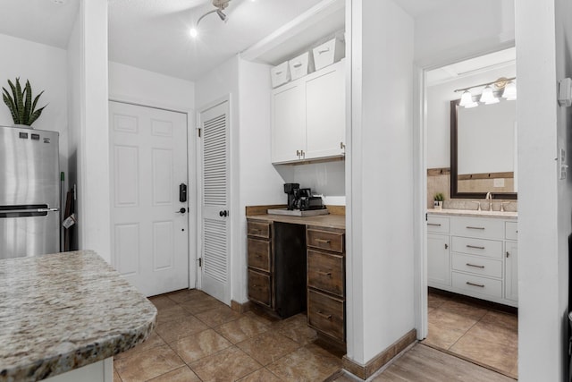 kitchen featuring white cabinets, stainless steel fridge, and sink