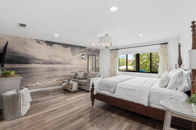 bedroom featuring hardwood / wood-style floors, a textured ceiling, and a notable chandelier