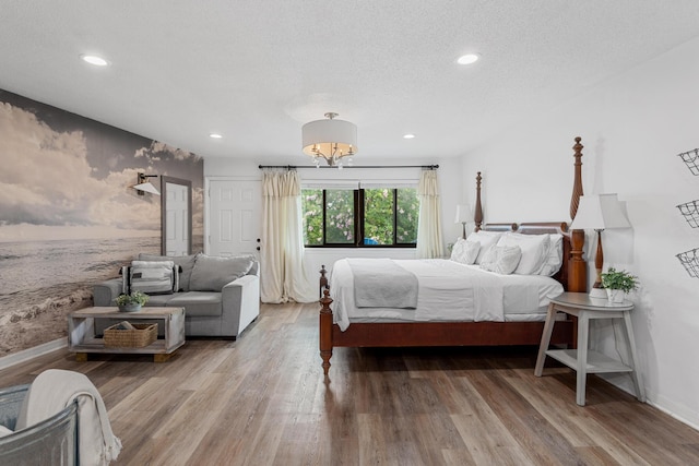 bedroom with a chandelier, a textured ceiling, and light wood-type flooring