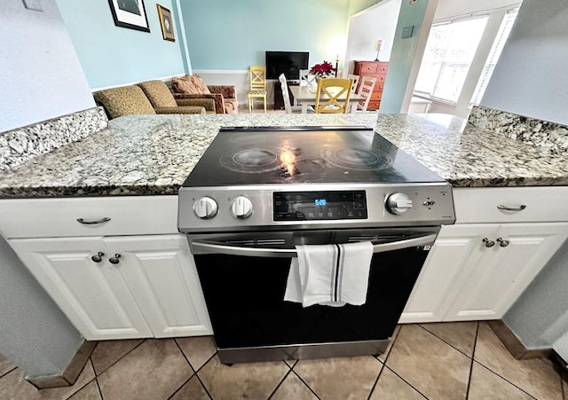 kitchen featuring light stone counters, white cabinetry, electric range, and light tile patterned floors