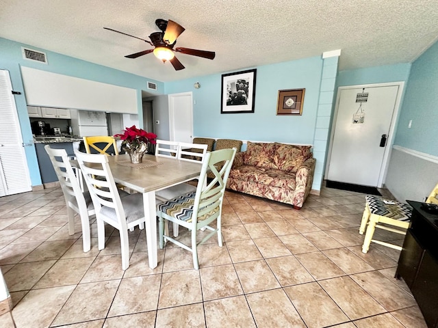 dining area featuring a ceiling fan, visible vents, a textured ceiling, and light tile patterned floors