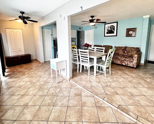 unfurnished dining area with light tile patterned floors, visible vents, a textured ceiling, and a ceiling fan