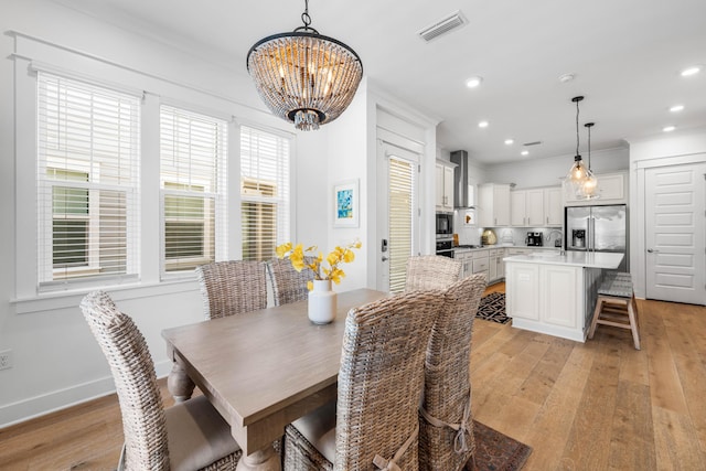 dining area with crown molding, sink, an inviting chandelier, and light hardwood / wood-style floors