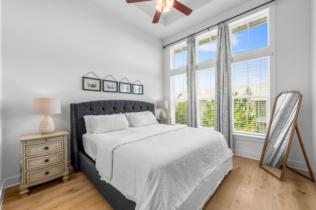 bedroom with vaulted ceiling, ceiling fan, light hardwood / wood-style floors, and multiple windows