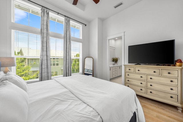 bedroom with ceiling fan, ensuite bathroom, and light hardwood / wood-style flooring