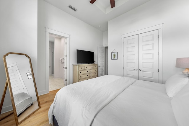 bedroom featuring ceiling fan, ensuite bathroom, light wood-type flooring, and a closet