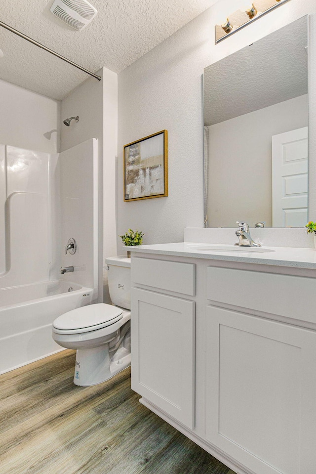 full bathroom with vanity, a textured ceiling, shower / tub combination, hardwood / wood-style flooring, and toilet