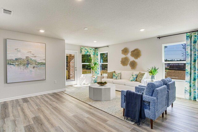 living room with light wood-type flooring and a textured ceiling