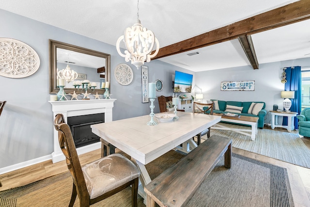 dining space with hardwood / wood-style floors, beamed ceiling, and a chandelier