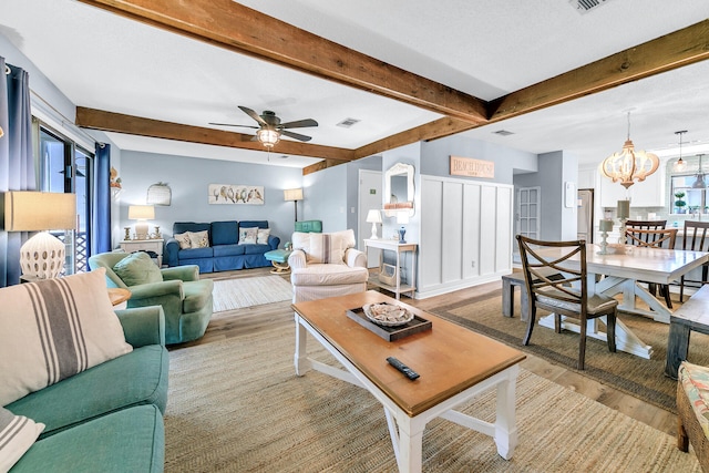 living room featuring beamed ceiling, a textured ceiling, ceiling fan with notable chandelier, and light hardwood / wood-style floors