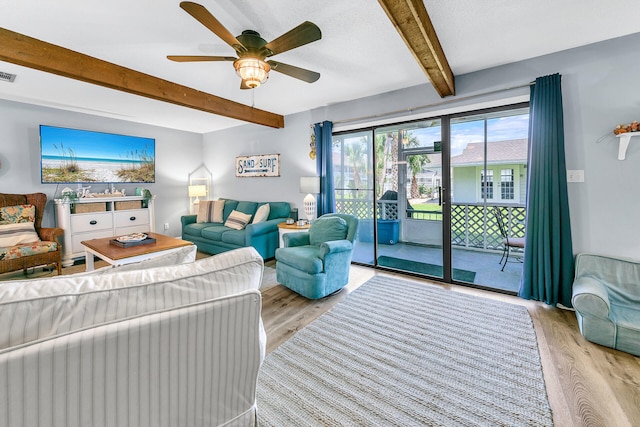 living room featuring beamed ceiling, ceiling fan, and light wood-type flooring