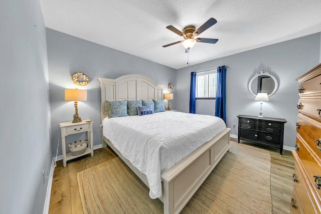 bedroom with ceiling fan, light hardwood / wood-style floors, and a textured ceiling