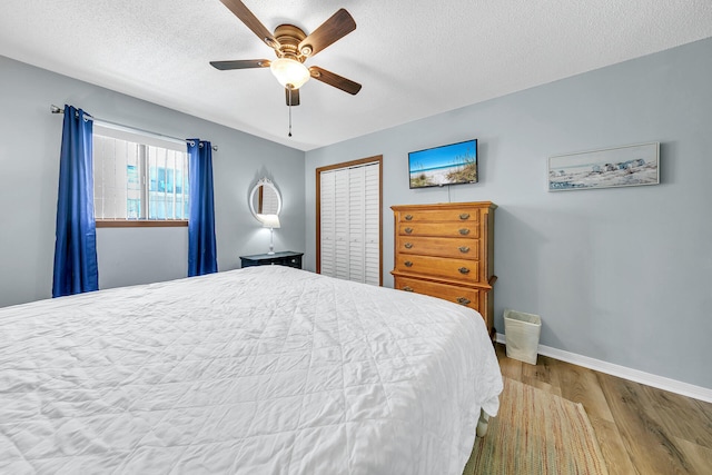 bedroom with a textured ceiling, a closet, light hardwood / wood-style flooring, and ceiling fan