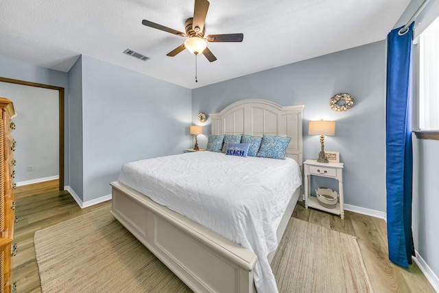 bedroom with ceiling fan, light hardwood / wood-style floors, and a textured ceiling