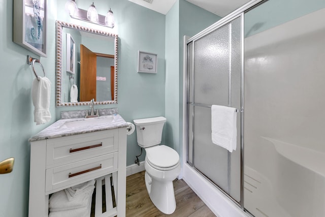 bathroom with toilet, an enclosed shower, wood-type flooring, and vanity