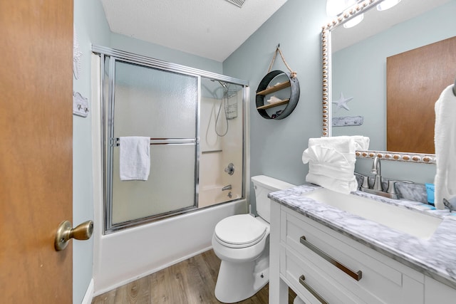 full bathroom featuring a textured ceiling, toilet, shower / bath combination with glass door, vanity, and hardwood / wood-style flooring