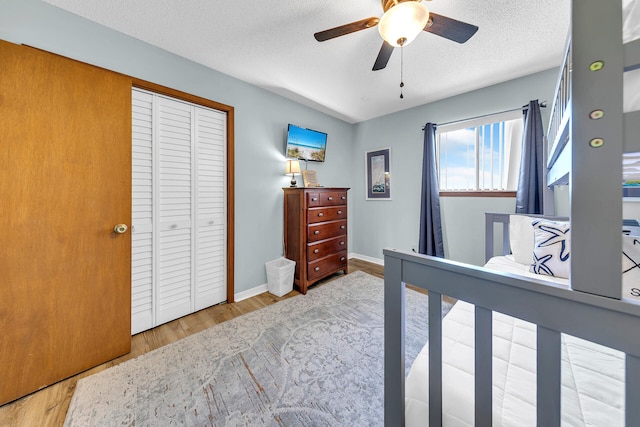 bedroom with ceiling fan, a closet, wood-type flooring, and a textured ceiling