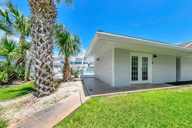 view of home's exterior with french doors, a patio, and a lawn