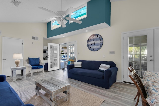 living room with ceiling fan, light hardwood / wood-style floors, high vaulted ceiling, and french doors