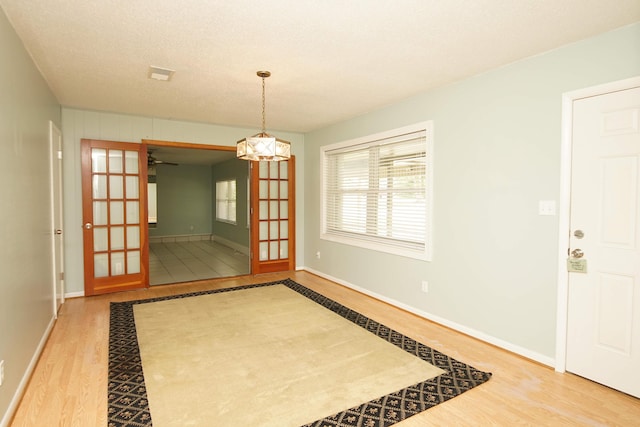 interior space featuring baseboards, a textured ceiling, visible vents, and wood finished floors