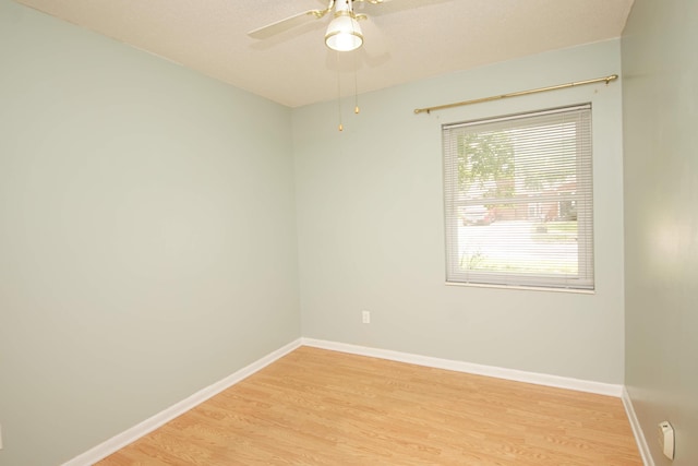 unfurnished room with light wood-type flooring, a ceiling fan, and baseboards