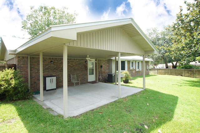 rear view of house featuring a lawn, a patio, fence, a carport, and brick siding