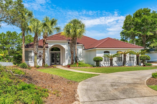 mediterranean / spanish-style house with french doors and a front lawn