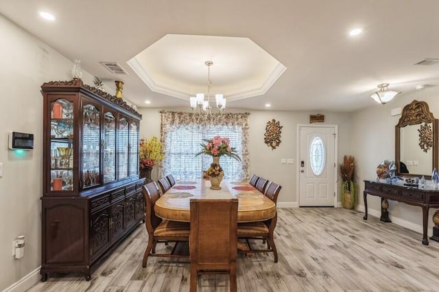 dining space featuring a notable chandelier, hardwood / wood-style flooring, and a raised ceiling