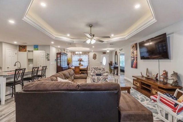 living room featuring light hardwood / wood-style floors, a raised ceiling, crown molding, and ceiling fan