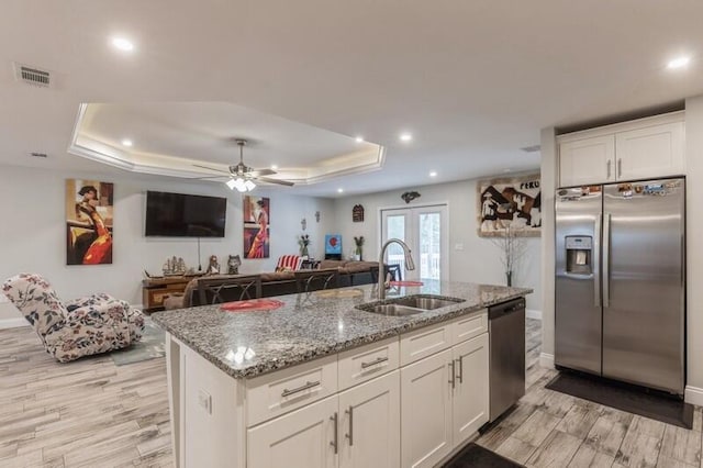 kitchen with appliances with stainless steel finishes, white cabinets, sink, and a tray ceiling